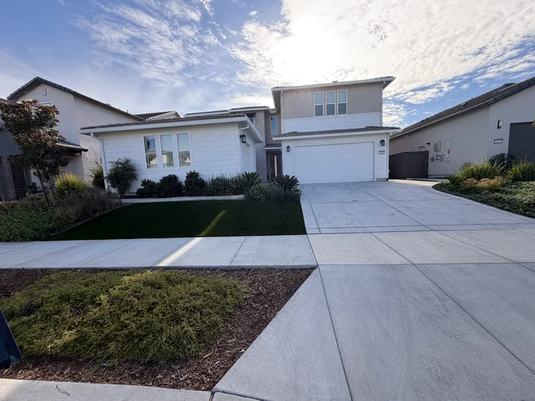 The front of the Maa Ghar home, with a lawn and a wide driveway.