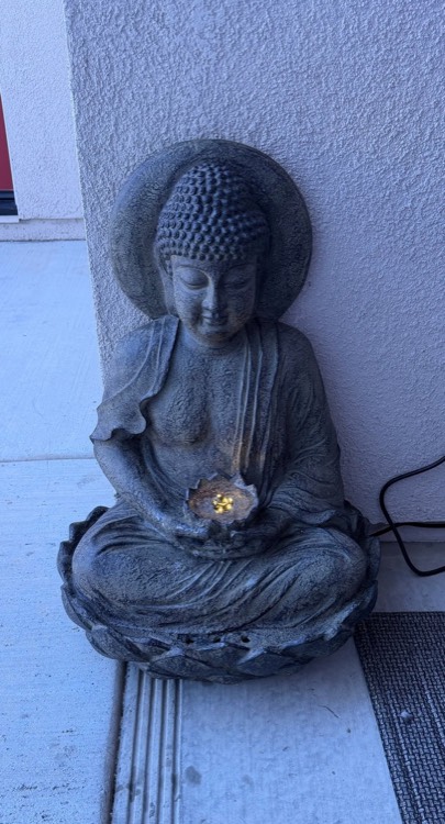 A stone Buddha and a lit candle on the patio.