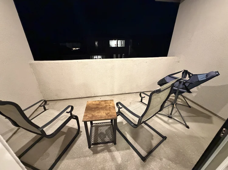 Two lounge chairs and a side table on the shared balcony.