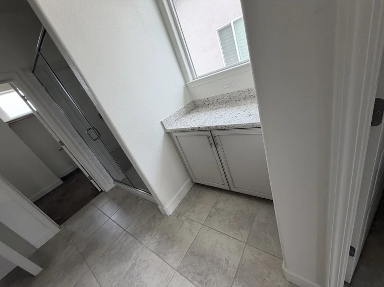 Cabinets and a stone counter beneath a window.