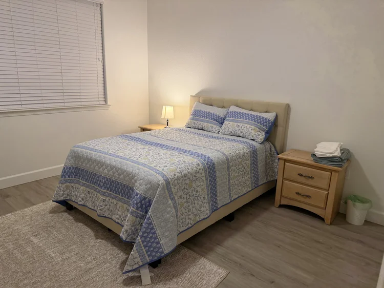 A furnished bedroom with a nightstand and a reading lamp.