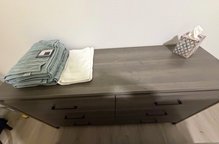 Fresh linens and towels folded on a bedroom dresser.