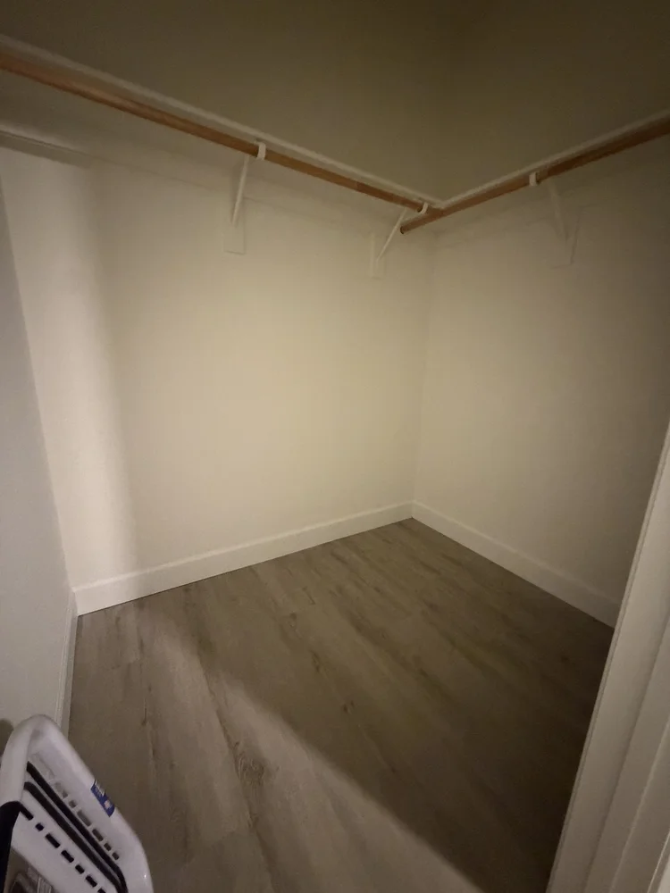 A walk-in closet with hanging rods on two walls.