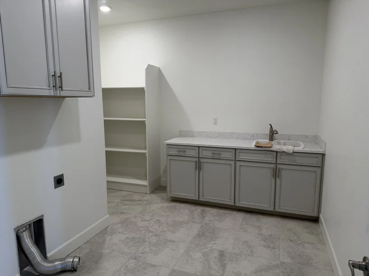 The laundry room counter, sink and shelving.